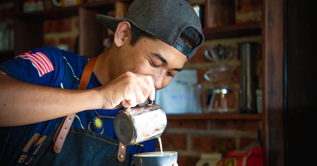 Can I take UHT milk to iceland? - Man in Blue Shirt and Gray Cap Making Cappuccino