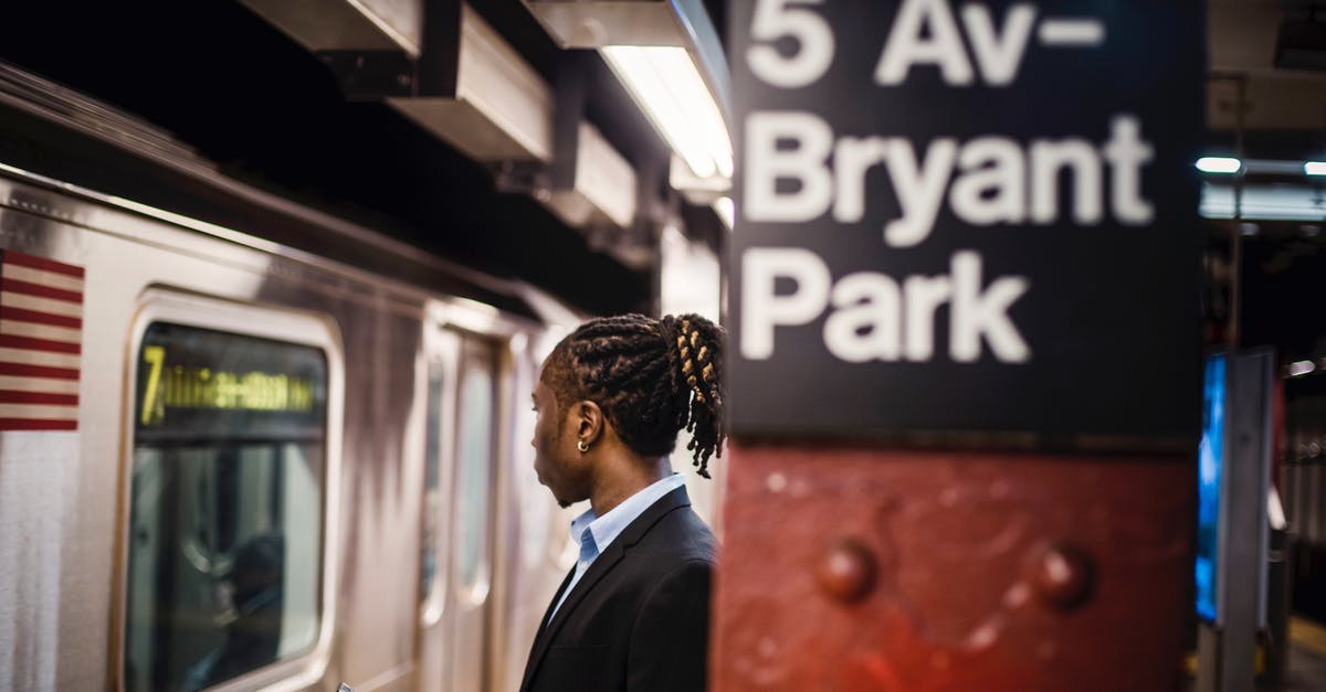 Can I transit through the US without a visa? - Black worker with smartphone waiting for subway at metro station