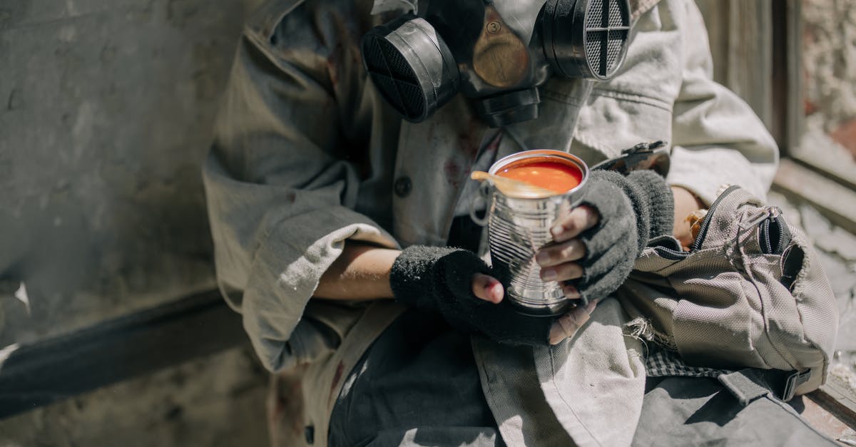 Can I transport canned food in hand luggage in Europe? - Person in Gray Jacket Holding White and Red Ceramic Mug