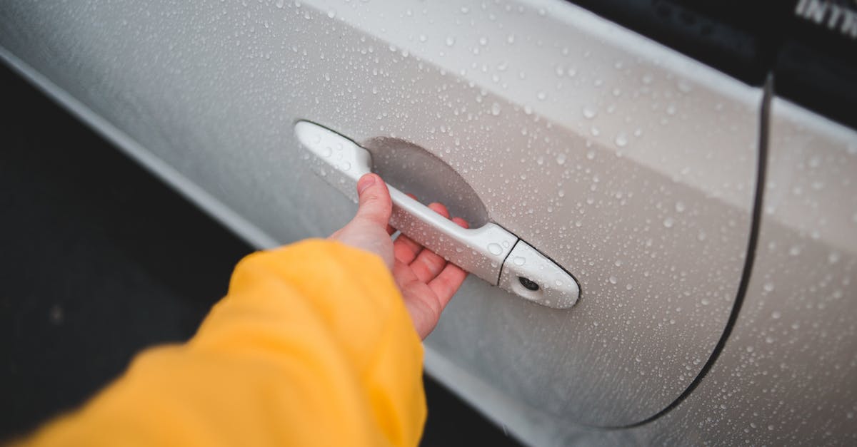 Can I transport fluid in Ryan Air's larger hand luggage? - From above of crop unrecognizable person in yellow wear holding handle of modern automobile door with water drips on surface