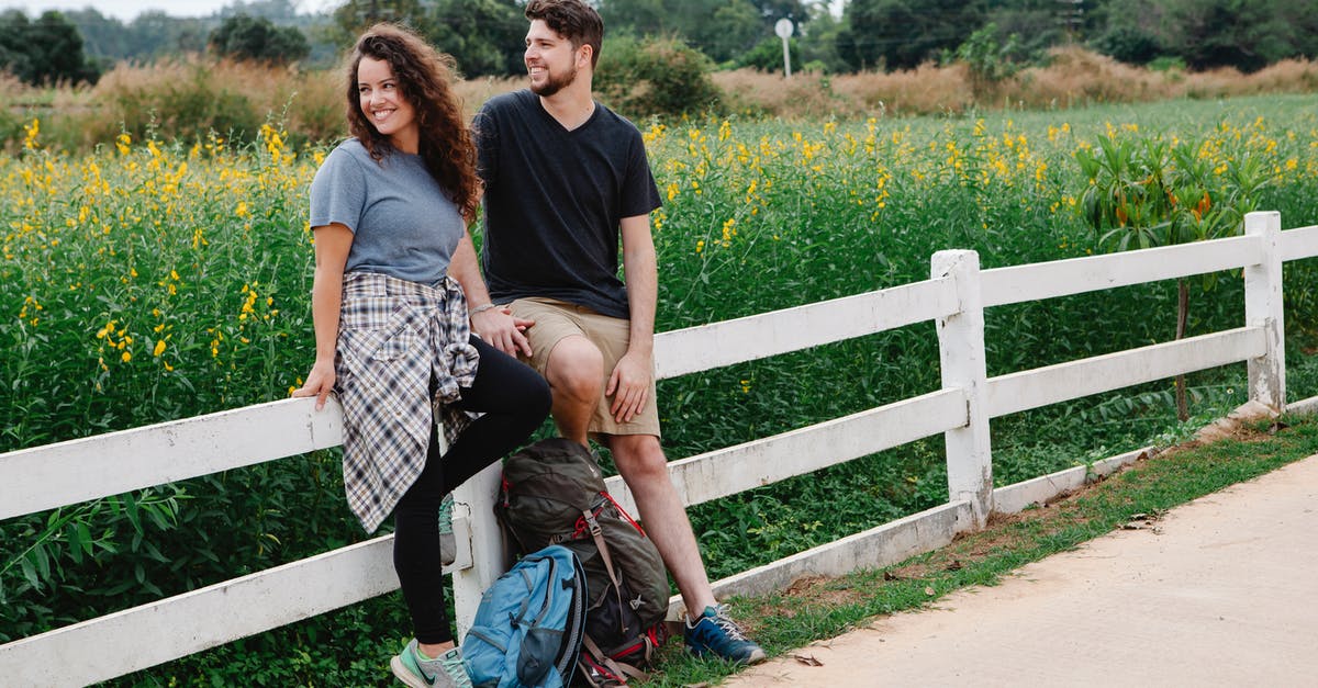 Can I travel days after my intended date of travel? [closed] - Joyful couple resting on fence in meadow and admiring nature