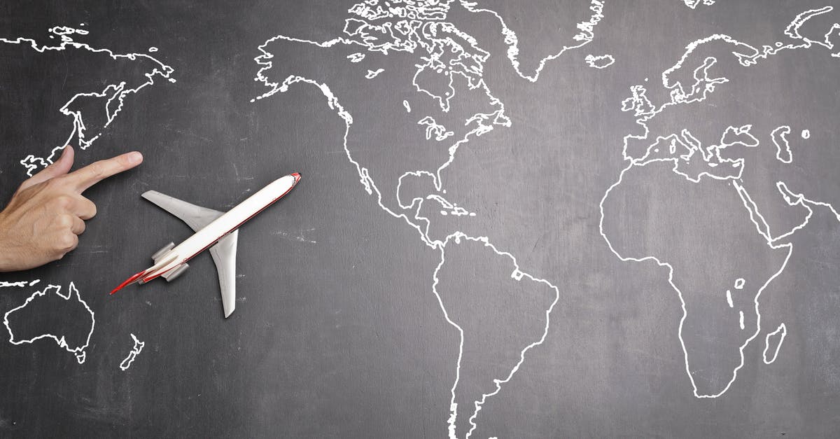 Can I travel from the USA to Spain with a one-way flight? - Top view of miniature airplane placed on over gray world map with crop hand of anonymous person indicating direction representing travel concept