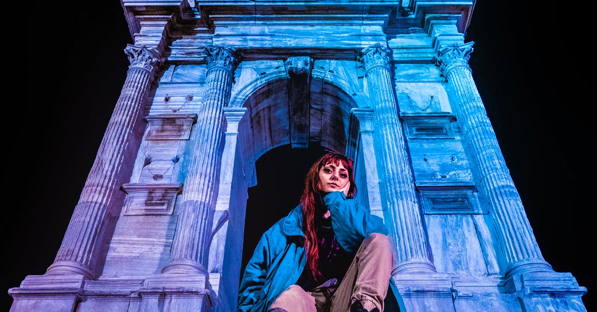 Can I travel to Italy with my permesso di soggiorno? - Woman in Blue Jacket Sitting Beside Arco di Traiano
