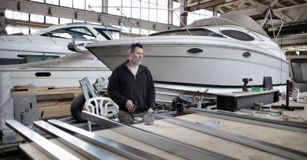 Can I travel to the northern part of Cyprus? - Focused adult worker preparing metal details in workshop with yachts