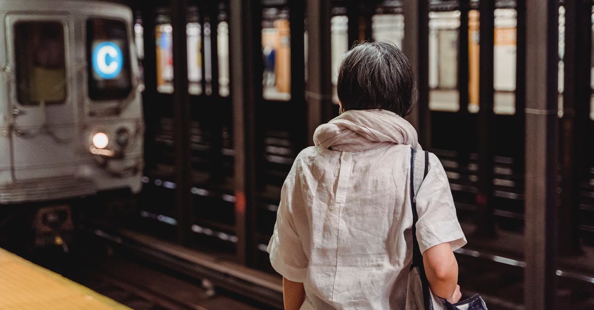 Can I travel while waiting for my new passport? - Woman Standing Inside the Subway Station Waiting for the Train