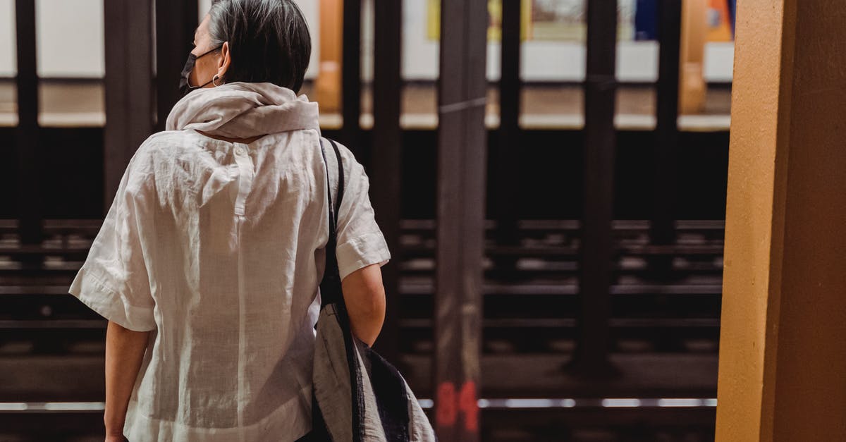 Can I travel while waiting for my new passport? - Woman Standing Inside the Subway Station Waiting for the Train