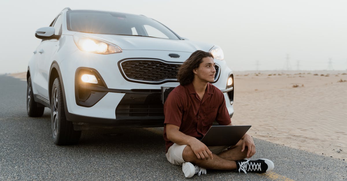 Can I use a second passport for Dubai layovers? - Man Sitting on the Road In Front of a White Car in the Desert