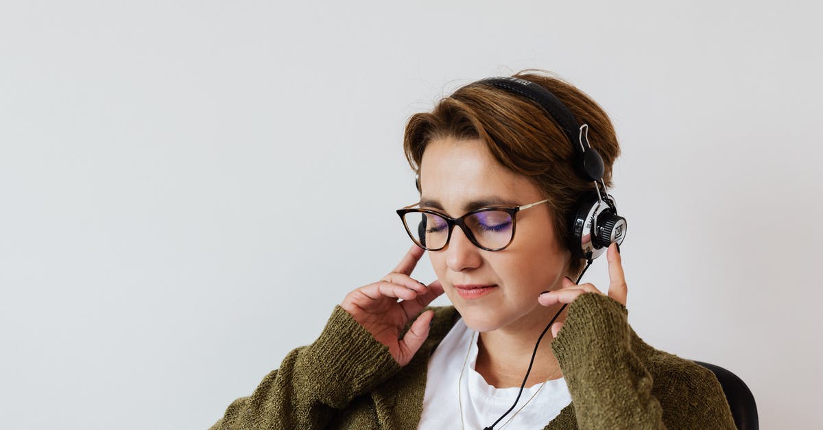 Can I use a Thomas Cook headset on a British Airways airplane? - Content glad female wearing eyeglasses and headphones listening to good music and touching headset while sitting with eyes closed against white wall
