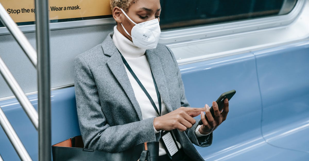 Can I use my German Transit Visa to transit in Netherlands? - Crop black focused woman using smartphone in metro train