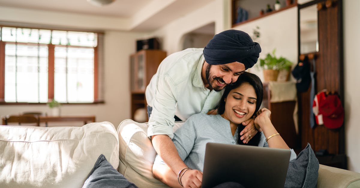 Can I use my school ID card for an Indian domestic flight? - Cheerful Indian man and woman in casual clothes embracing and surfing internet on laptop while hugging in cozy living room during daytime