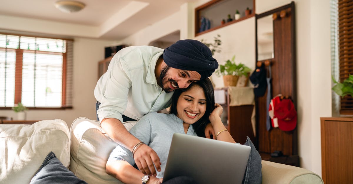 Can I use my school ID card for an Indian domestic flight? - Cheerful ethnic couple surfing laptop together at home