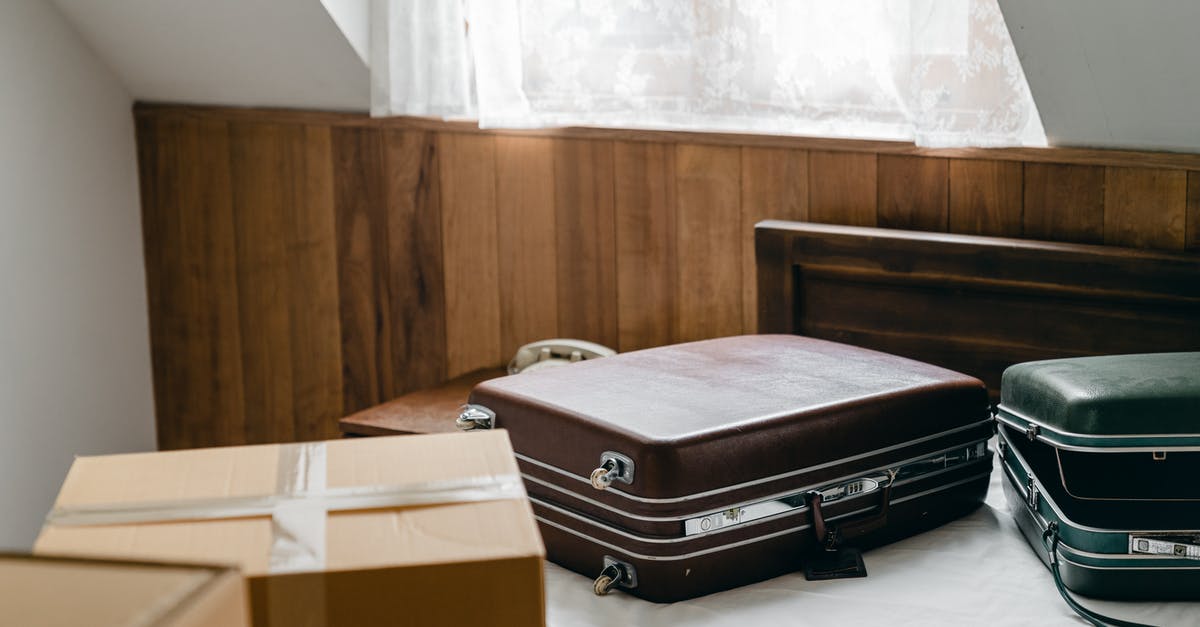 Can I use plastic bag as a personal item - From above of brown and green vintage suitcases and packed carton boxes placed on bed with sheet in light room with sloping roof