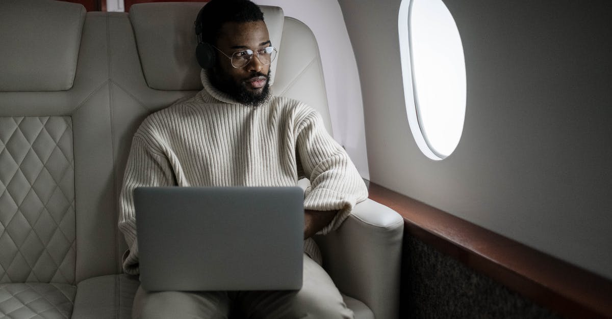 Can I use regular headphones on transatlantic British Airways 747 flights? - Man in White Sweater Sitting on Couch Using Macbook