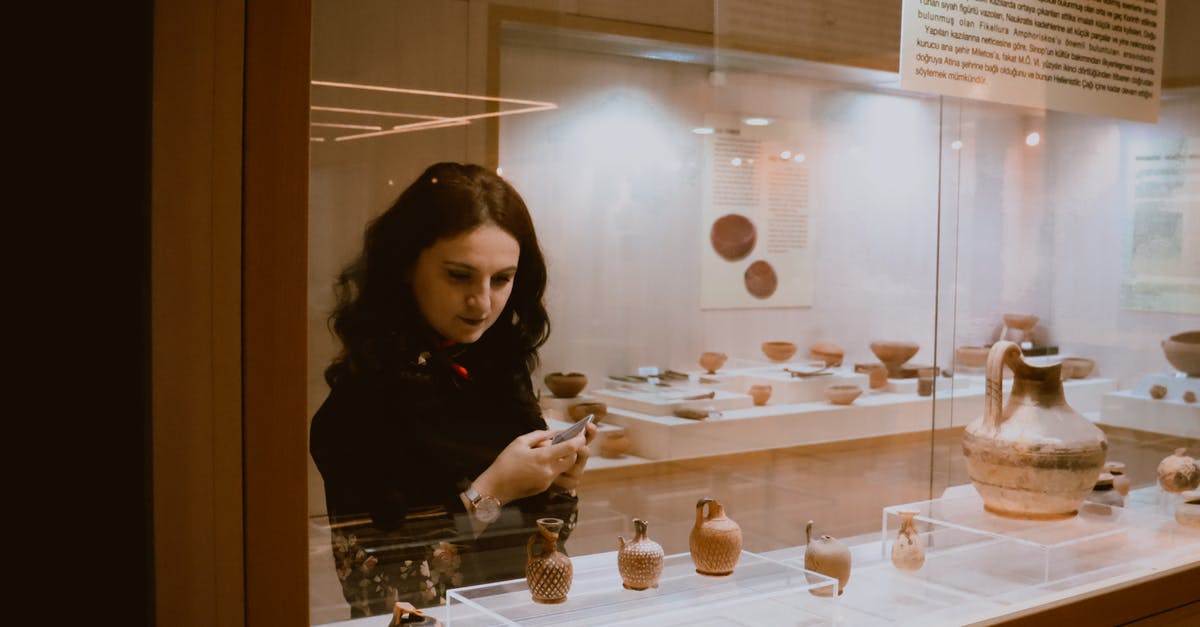 Can I visit other Schengen countries on a long-term Schengen visa or residency permit? - Woman examining vases in exhibition hall