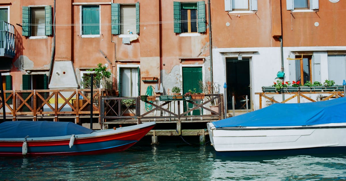 Can I visit Poveglia island in Venice lagoon? [closed] - Old coastal town near canal with moored boats