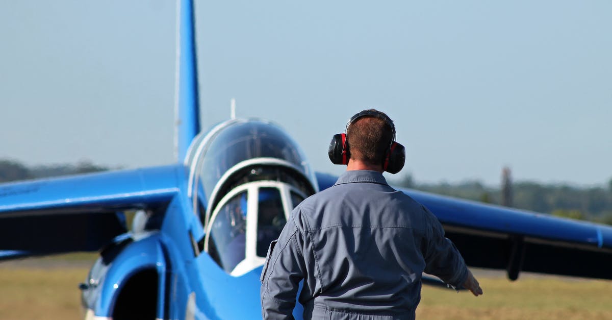 Can Noise Cancelling headphones block the overhead PA on a plane? - Man in Noise Cancelling Headphones Approaching Blue Airpla