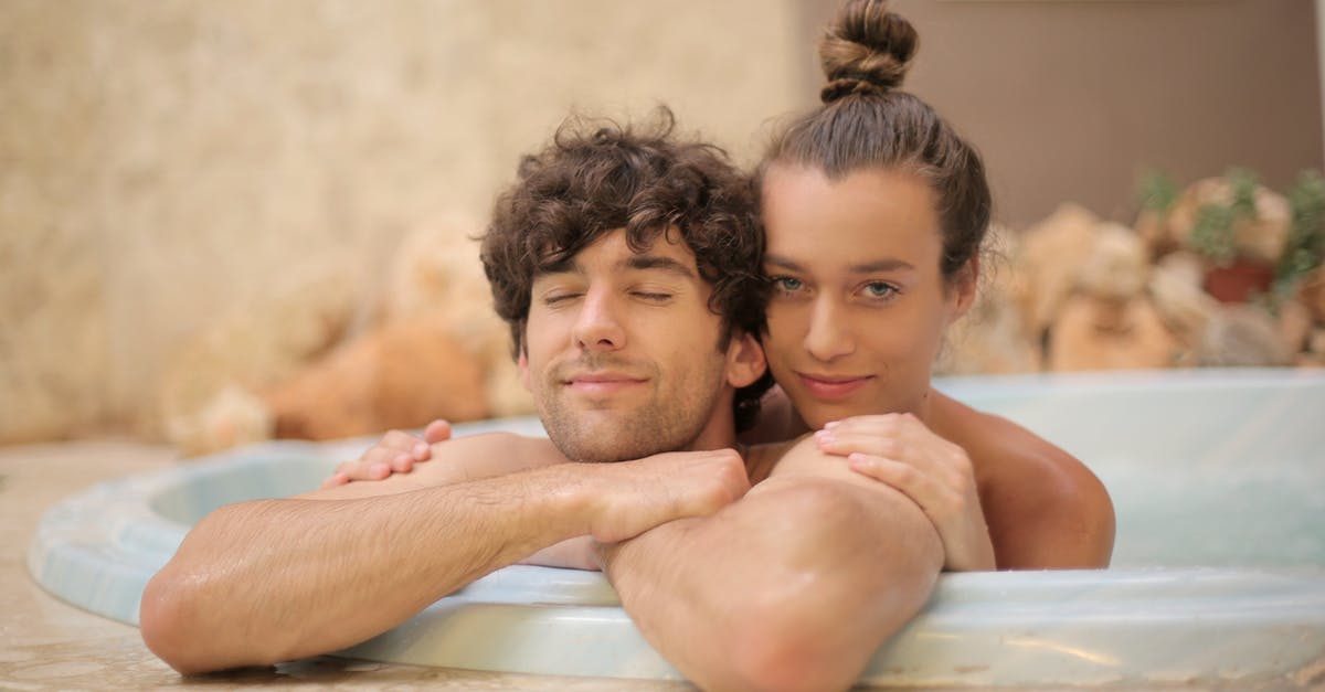 Can one take away hotel slippers? [duplicate] - Young cheerful man and woman taking bath together enjoying holidays on blurred background of spa resort with marble interior and having romantic moments