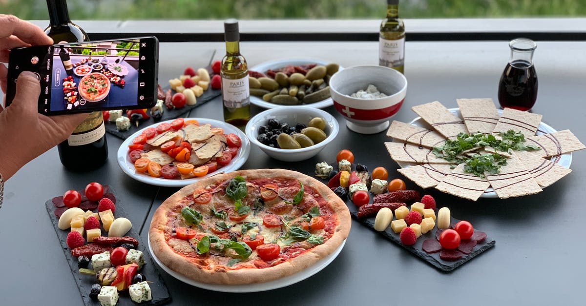 Can person take a toothpick from a restaurant in Japan? - Unrecognizable person photographing table with pizza and assorted snacks