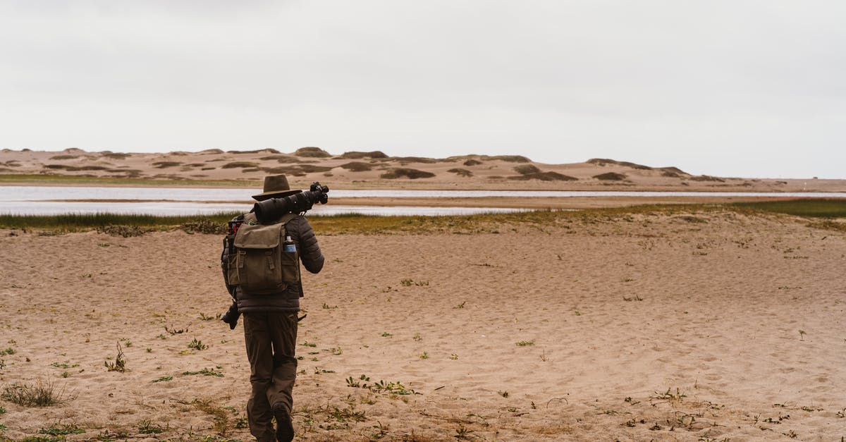 Can Somebody travel with their gun internationally? [duplicate] - Man Walking With A Backpack And Camera Equipment On Sandy Ground