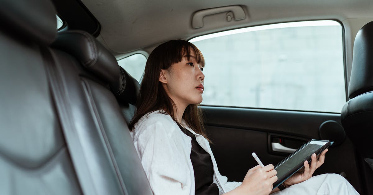 Can UK student visa refusal impact on Australian Student visa application? - From below side view of contemplative Asian lady  in black and white outfit sitting in car passenger seat and working on tablet with stylus