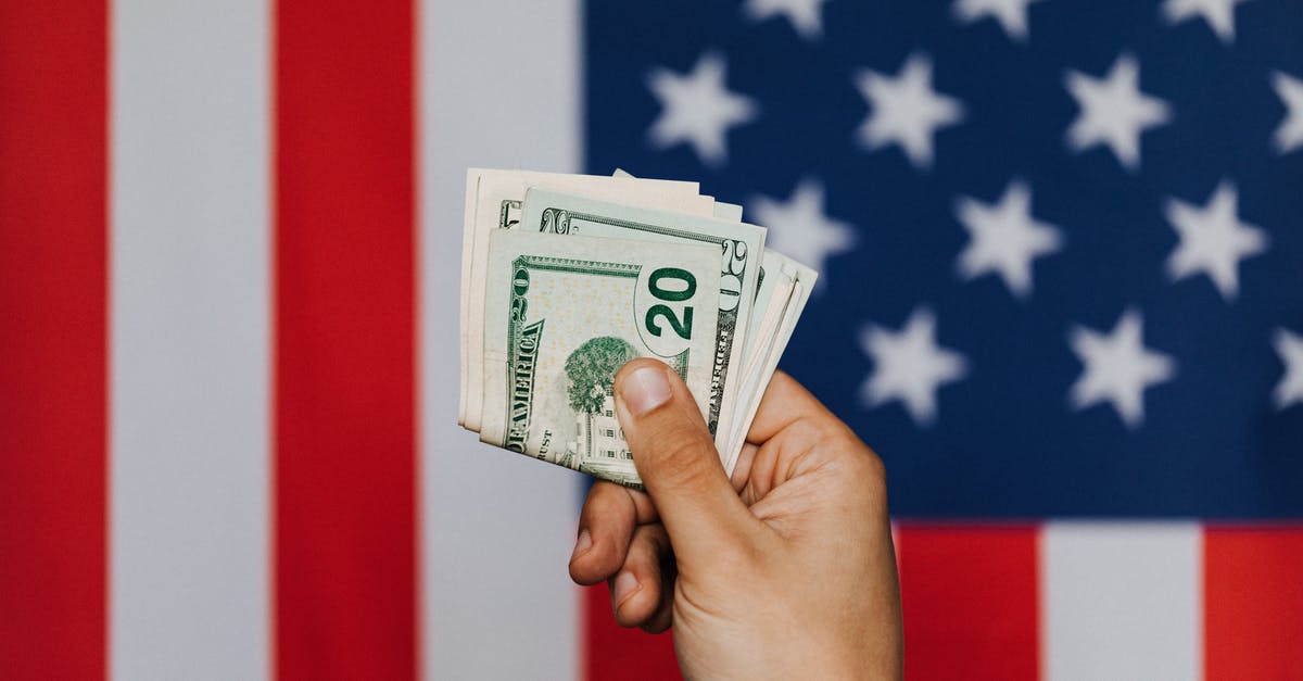 Can US citizens overstay in American Samoa? - Unrecognizable male demonstrating dollars before official flag of USA on background