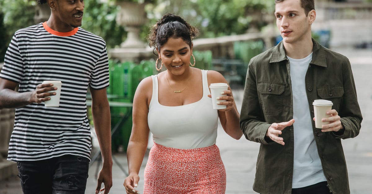 Can we share the Go Pass? - Joyful young multiethnic students in casual clothes discussing lessons while walking together in park with takeaway cups of coffee