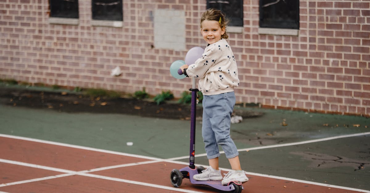 Can you bring an electric scooter on Flixbus? - Content child in casual clothes with balloons riding electric scooter and looking at camera in town against building