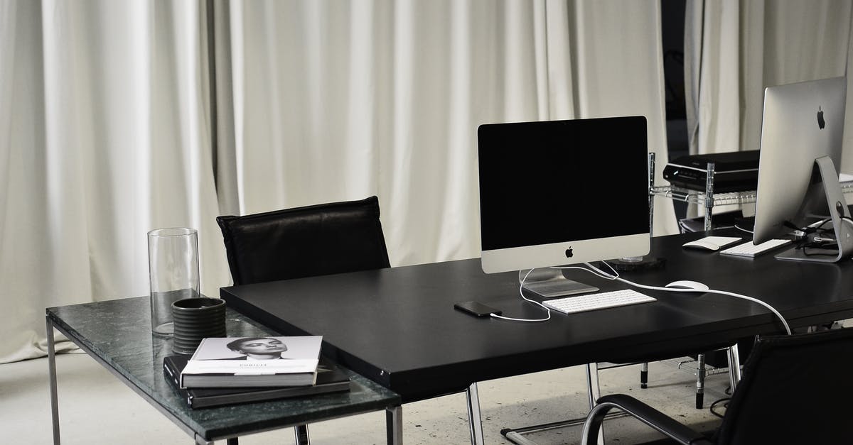 Can you charge your phone "airside" at Malaga Airport (AGP) - Black and white of workspace of office with computers placed on table with wireless mouse and keyboard near smartphone