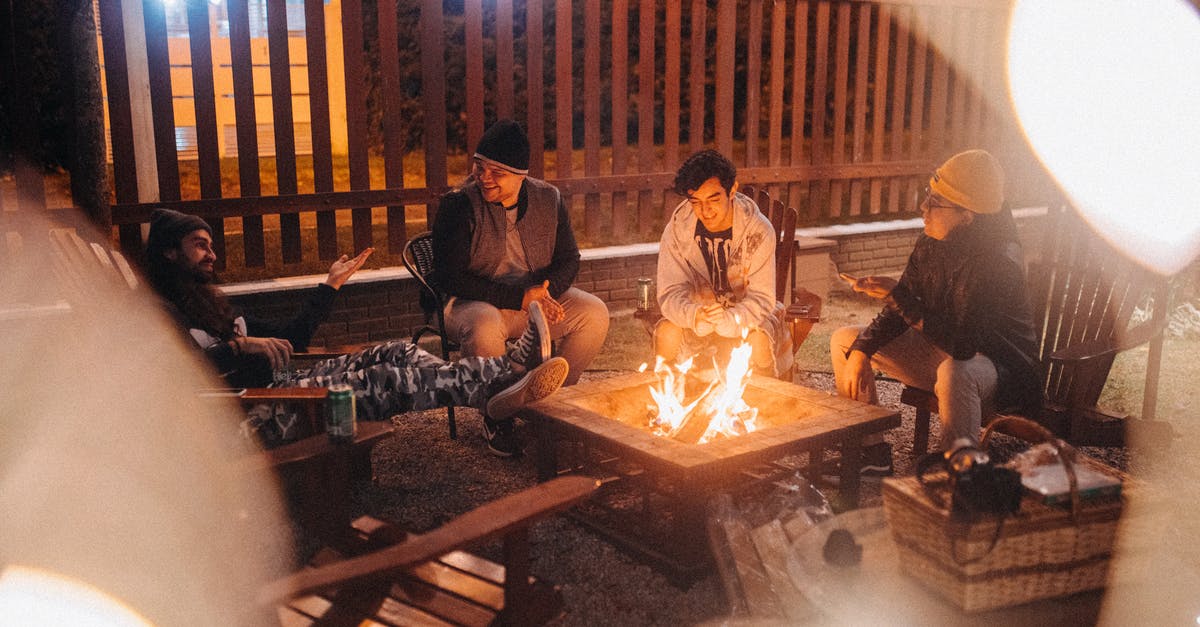 Can you really get around everywhere with only speaking English? - Friends talking against burning fire at dusk in campsite