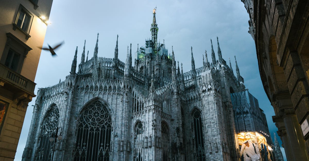 Can you see Putin in Duomo di Milano? - From below of Milan Cathedral of Nativity of Saint Mary with facade advertising on one side under cloudy sky on quiet evening