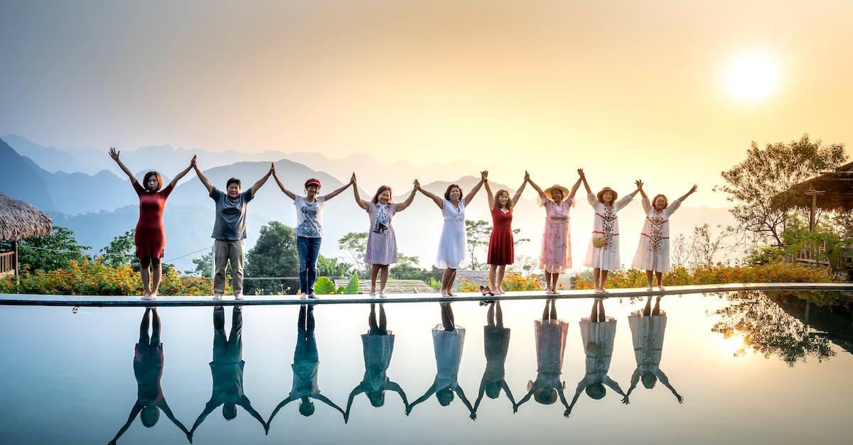Can you share frequent flyer status with people in your travel group? - Happy full body ethnic people in summer clothes standing on poolside and holding hands with raised arms near calm water on sunset with amazing mountains on background Can you share frequent flyer status with people in your travel group? - Happy full body ethnic people in summer clothes standing on poolside and holding hands with raised arms near calm water on sunset with amazing mountains on background