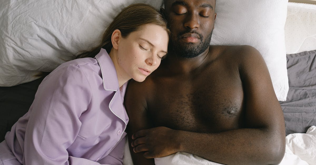 Can you sleep in Canberra airport or does it close overnight? - Top view of woman in nightwear and African American man sleeping together on comfortable bed in light bedroom at home