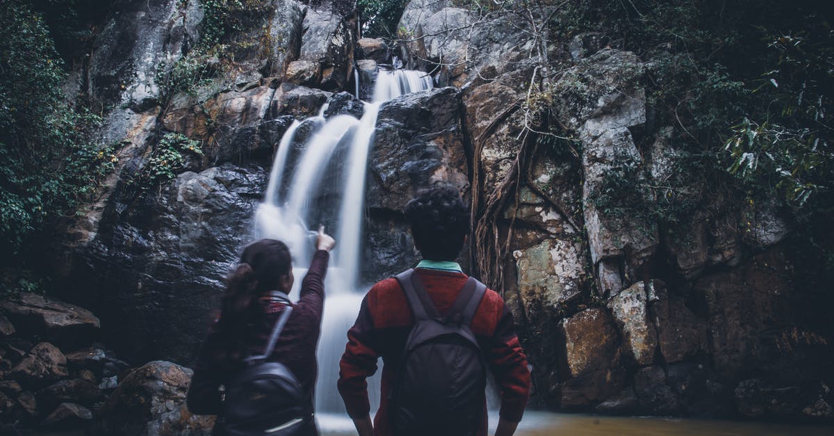 Can you split India in distinct focal points to travel to? - Back view of unrecognizable female traveler in casual clothes and backpack pointing at fast Midubanda Waterfall while admiring nature during trip in India with boyfriend