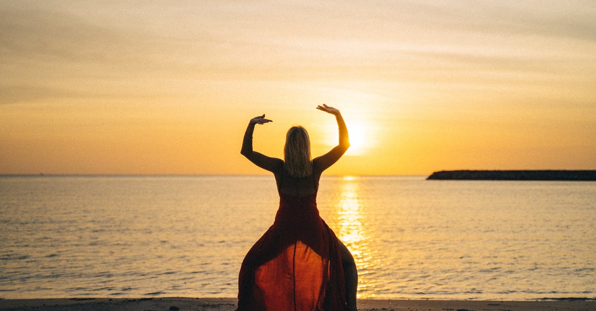 Can you stretch a Coast Starlight ticket over multiple days? - Back view of female with raised hands doing yoga standing on sandy beach with face towards calm sea and sunset in summertime