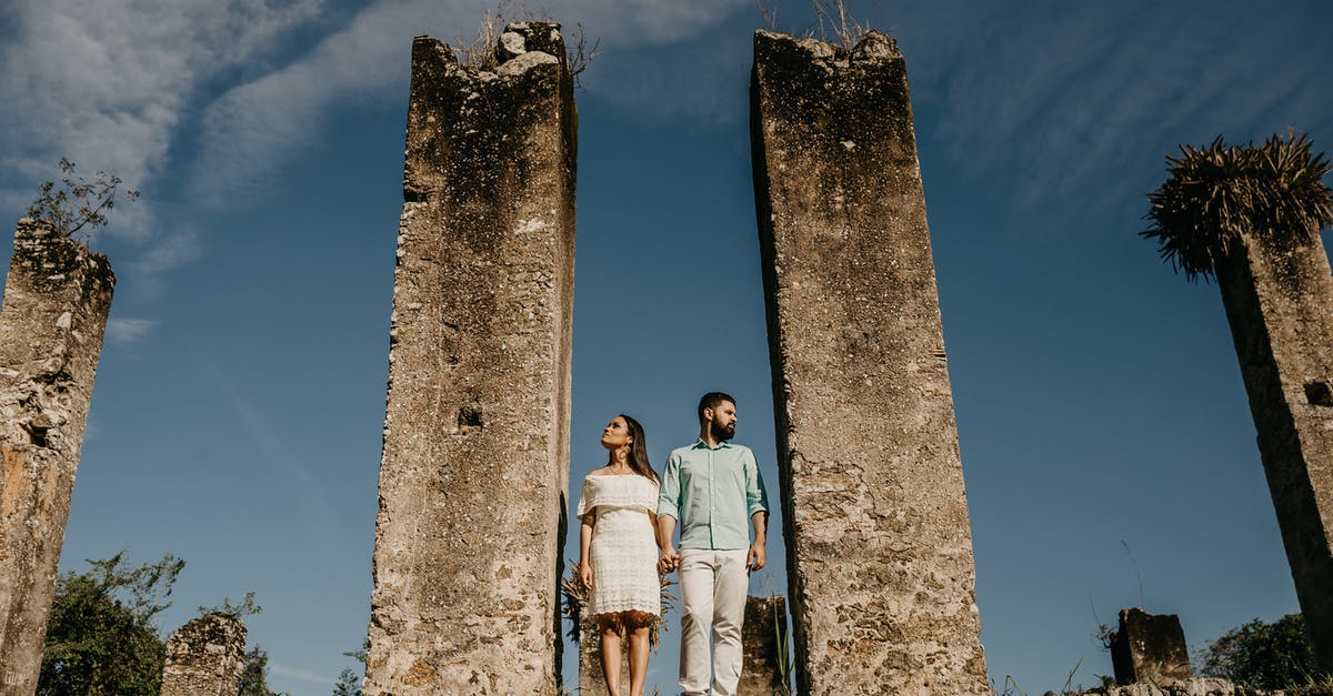 Can you visit the abandoned Nicosia Airport? - From below full body of male and female standing together near remains of ancient building and holding hands while looking away in sunny day