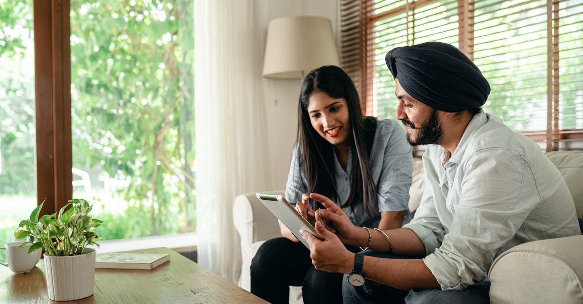 Can you work online with an Indian Tourist Visa? - Young Indian man in casual outfit and turban working on project with female colleague using tablet in cozy workplace