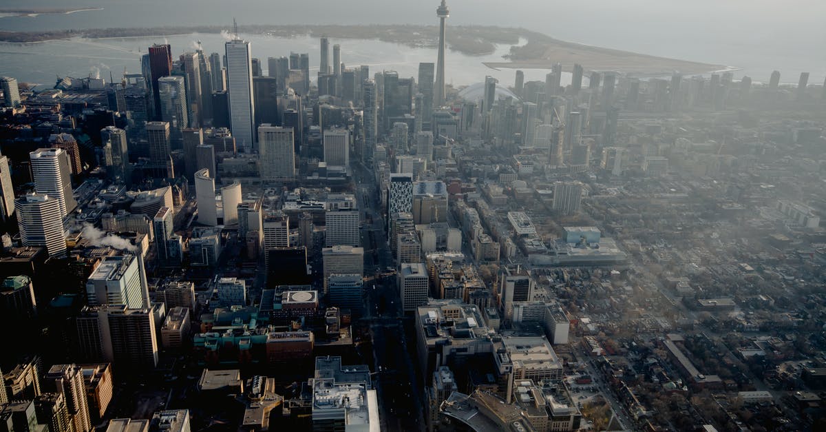 Canada temporary residence visa - Aerial view of megapolis streets with residential buildings and office skyscrapers on river coast in Canada