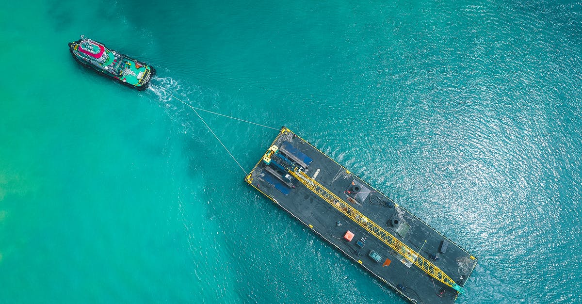 Canadian Transit Visa - Passport Delivery Fee - Aerial view of modern vessel floating on rippling blue seawater and pulling big platform