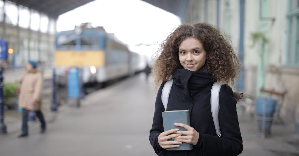 Cancelling only one passenger in a booking - Positive young lady with backpack and book standing on platform