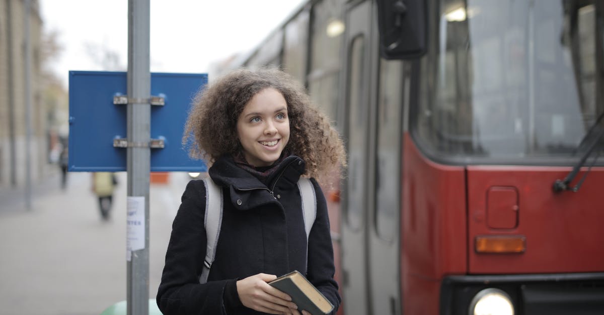 Cancelling only one passenger in a booking - Cheerful young lady with book waiting for bus on street