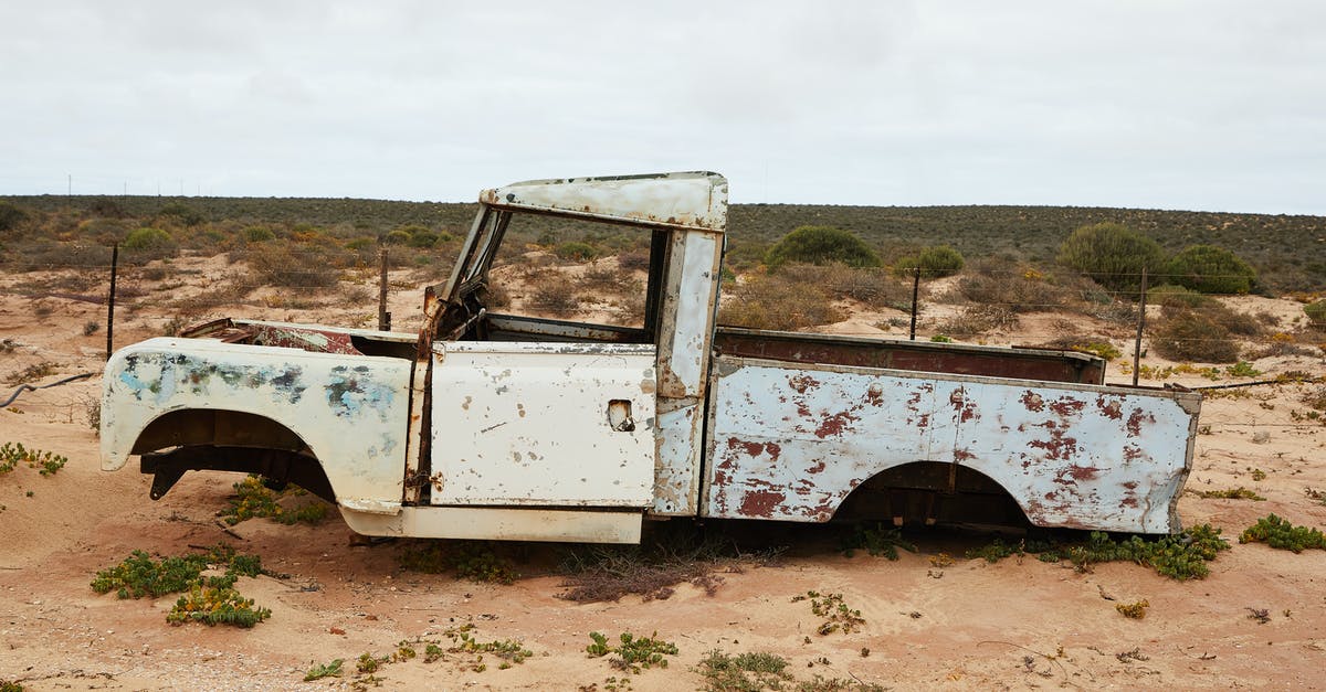 Car damage caused by potholes in the EU, what to do? - Rusty abandoned car near fence in desert