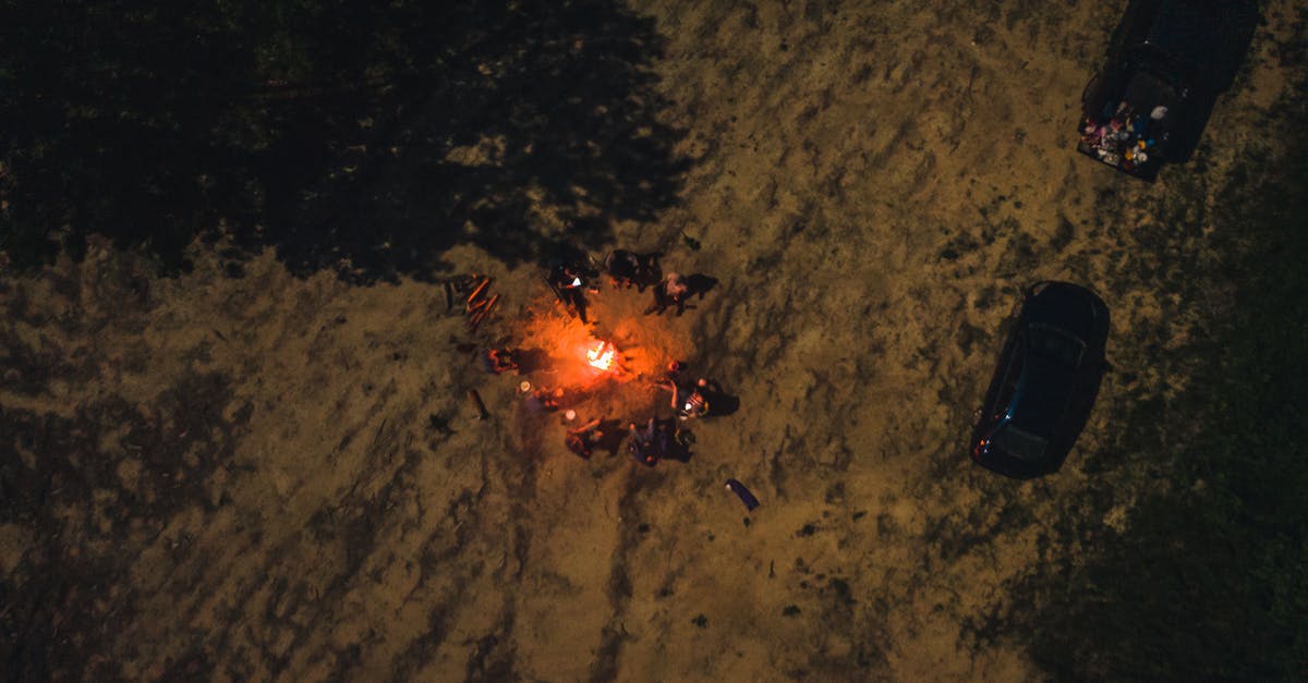 Car ferries time distance [closed] - Drone view of group of friends spending time together by flaming bonfire in woodland at night