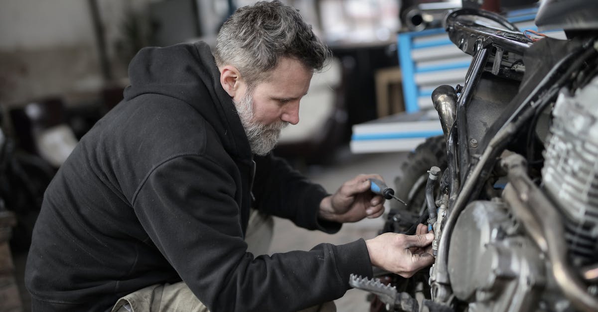 Car hire in Austria with ski equipment - Bearded man fixing motorcycle in workshop