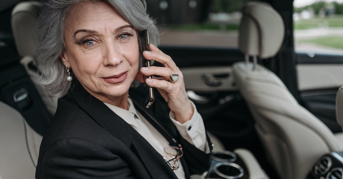 Car rental at 20 years old in UK - Woman in Black Blazer Holding Smartphone