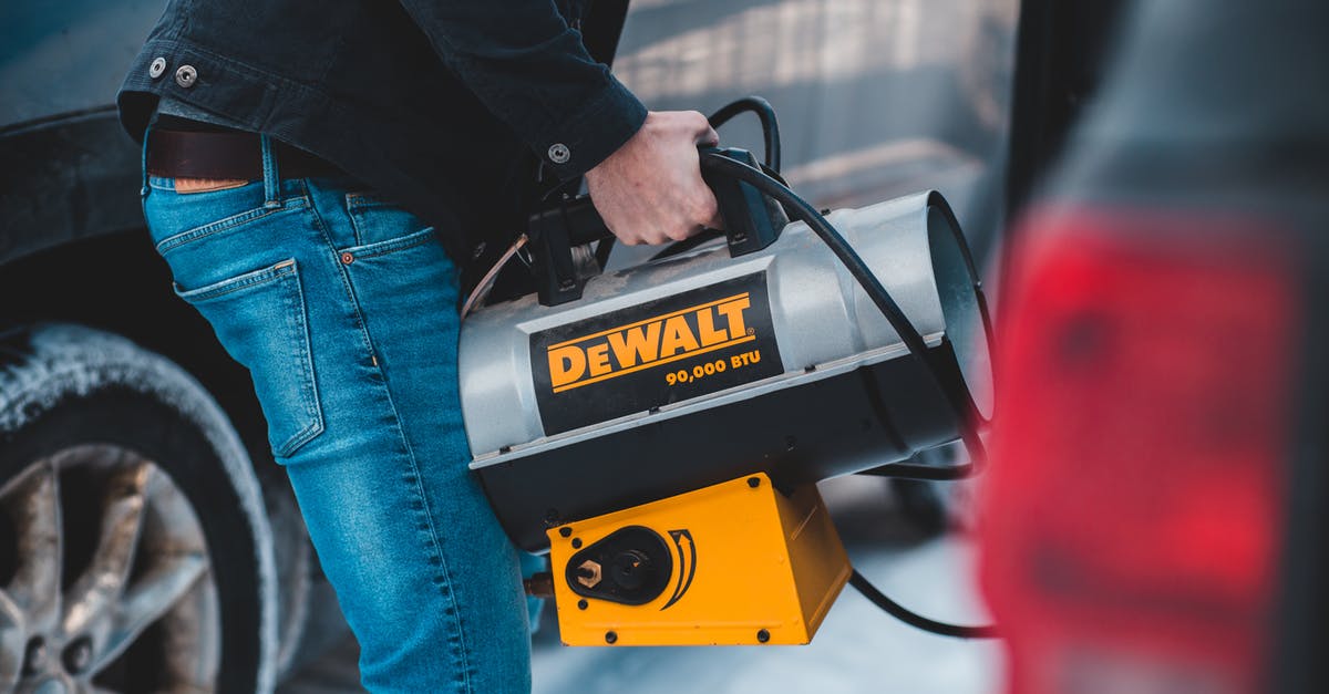 Car rental cancellation because of lack of winter tires - Faceless man carrying portable heater standing near cars on street