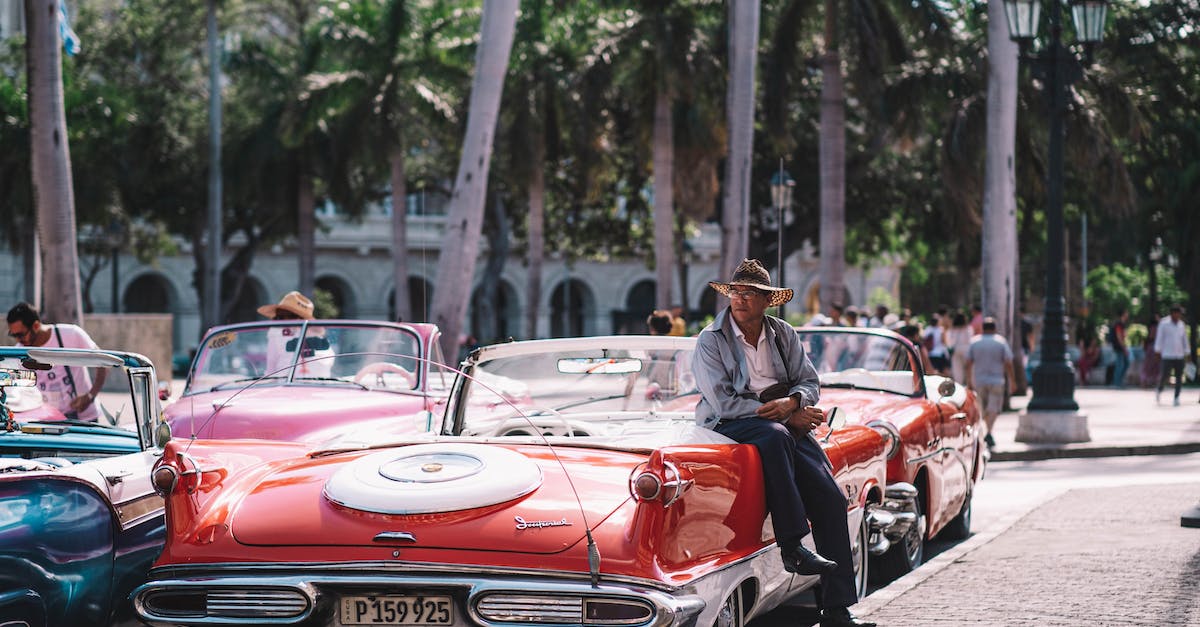 Car rental in Cuba - A Man Sitting on Red Vintage Car