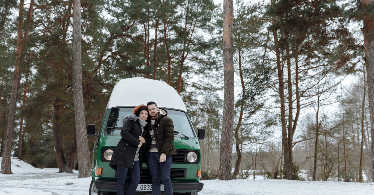 Car rental in Germany - are winter tyres included? - Couple In Front of a Green Van while in the Forest