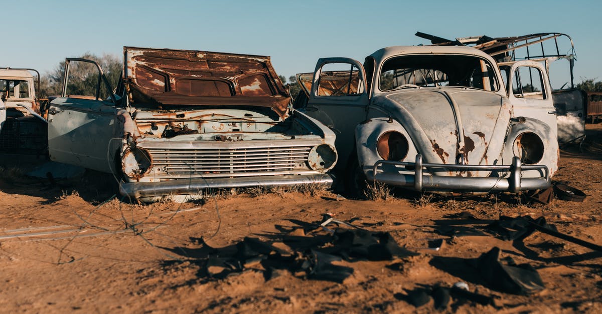 Car rental prices different for foreigners - Damaged retro cars in desert under blue sky