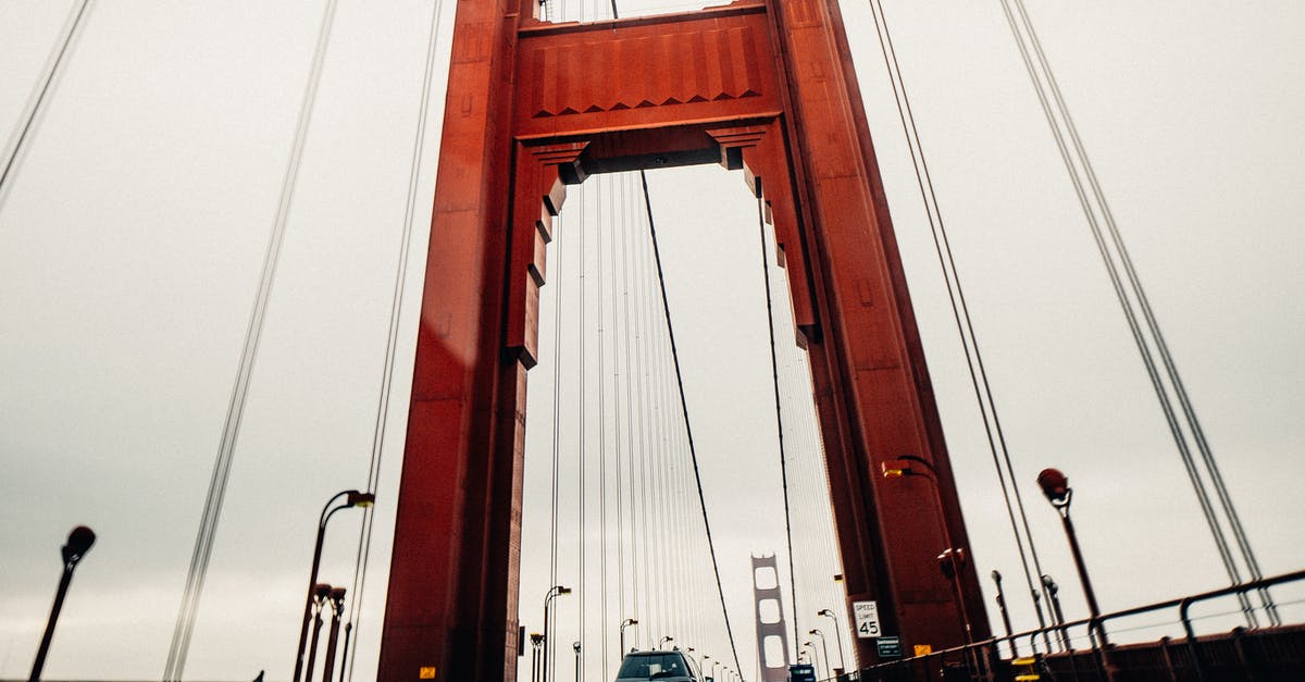 Car rentals cross-border between USA & Canada - Cars riding along asphalt surface of famous Golden Gate Bridge in San Francisco on cloudy overcast day