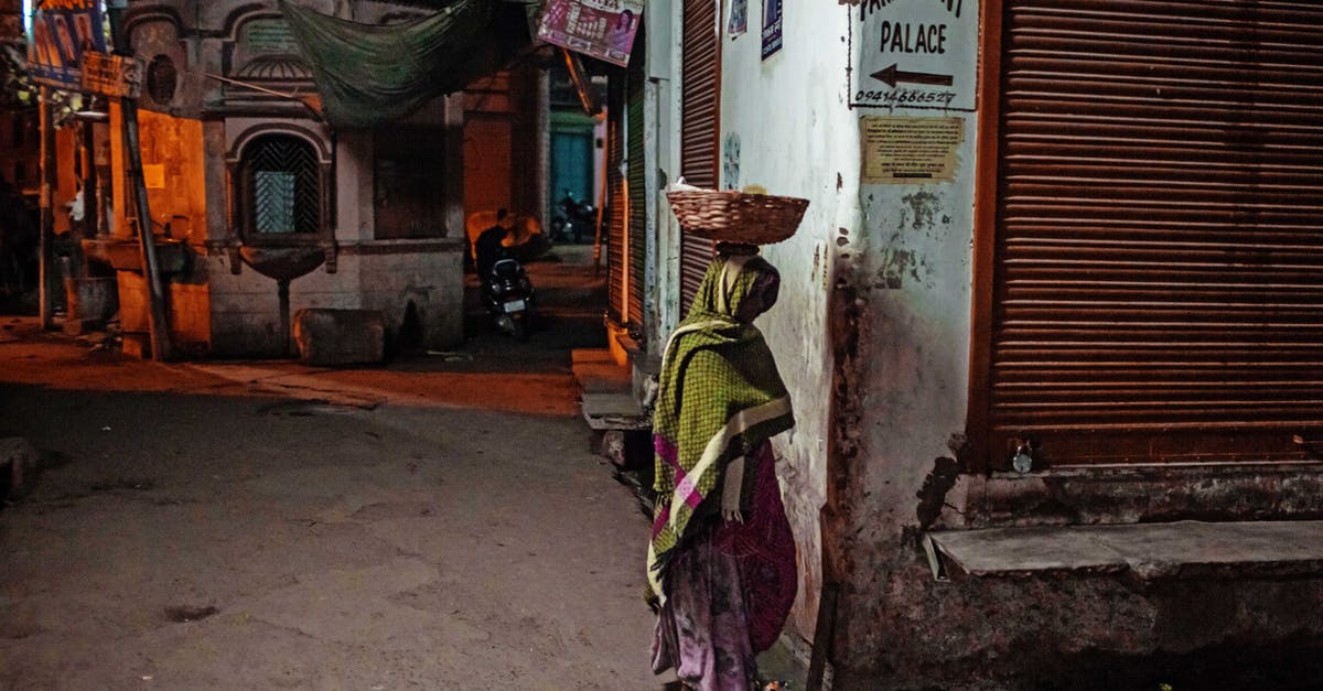 Carry Diamond earrings from India to US [duplicate] - Full body anonymous Indian woman in headscarf carrying basket on head walking on shabby town street